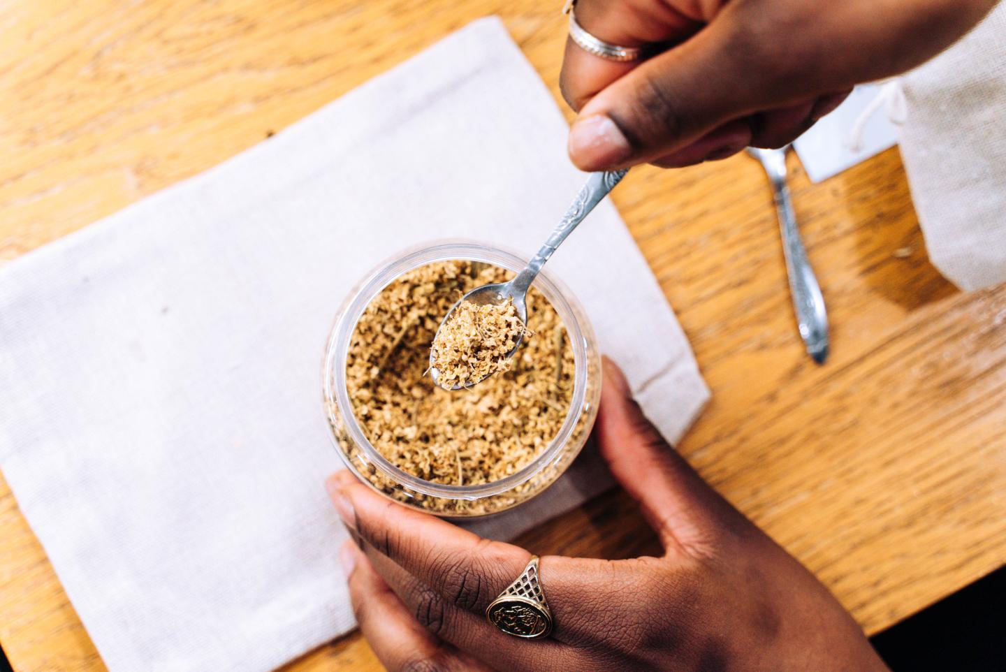 photo of hands holding a jar of herbs and spoon